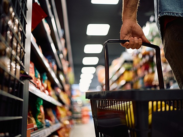 person holding shopping basket in supermarket shopping for groceries